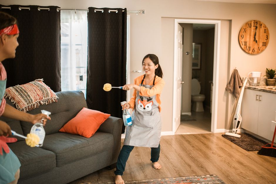 A cheerful couple engages in a playful cleaning session in their home.